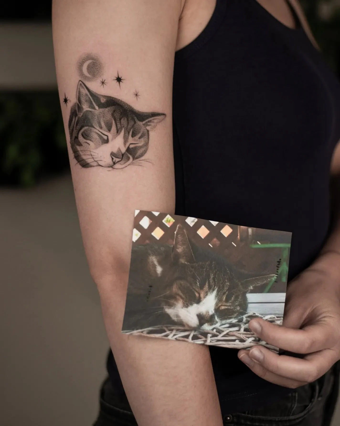 Zbliżenie tatuażu przedstawiającego śpiącego kota, otoczonego księżycem i gwiazdami; obok widoczna fotografia kota będąca punktem odniesienia.
