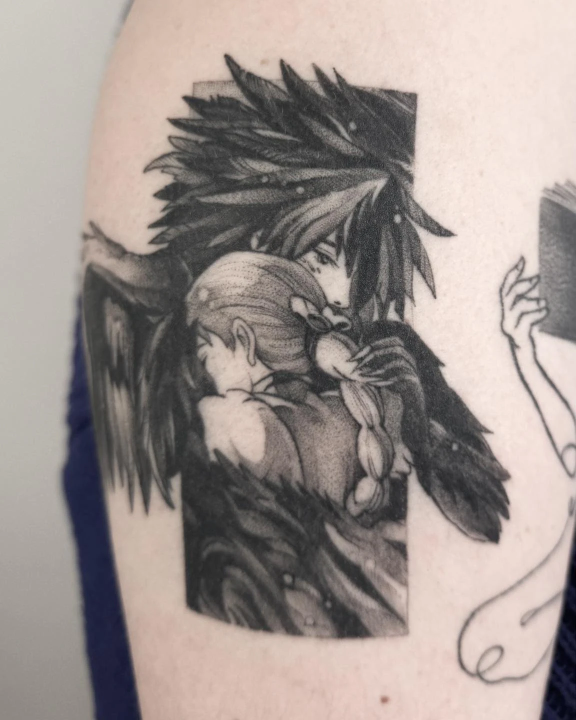 Wygojony czarno-szary tatuaż inspirowany filmami Studia Ghibli, przedstawiający dwie postacie otoczone dużymi skrzydłami.