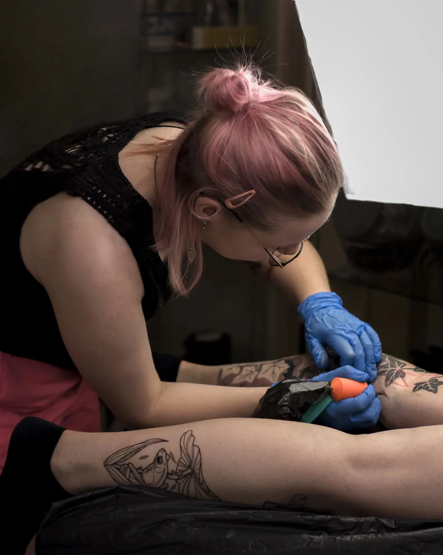 Klara Keczyńska wykonuje tatuaż w rękawiczkach ochronnych; zbliżenie pokazuje pracę maszynką na wytatuowanej kończynie.