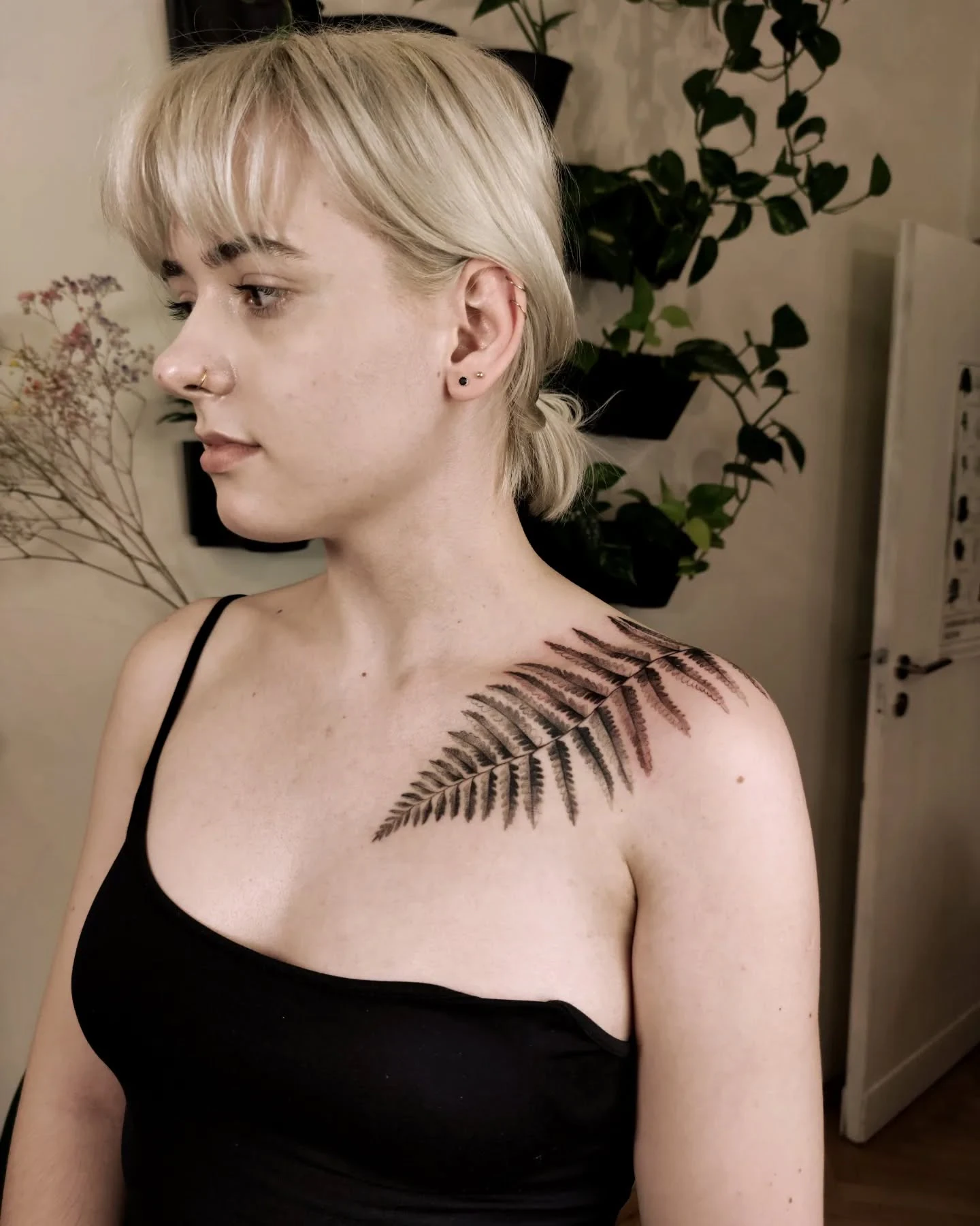 Wygojony tatuaż paproci na obojczyku i ramieniu modelki, pokazany z kilku perspektyw.