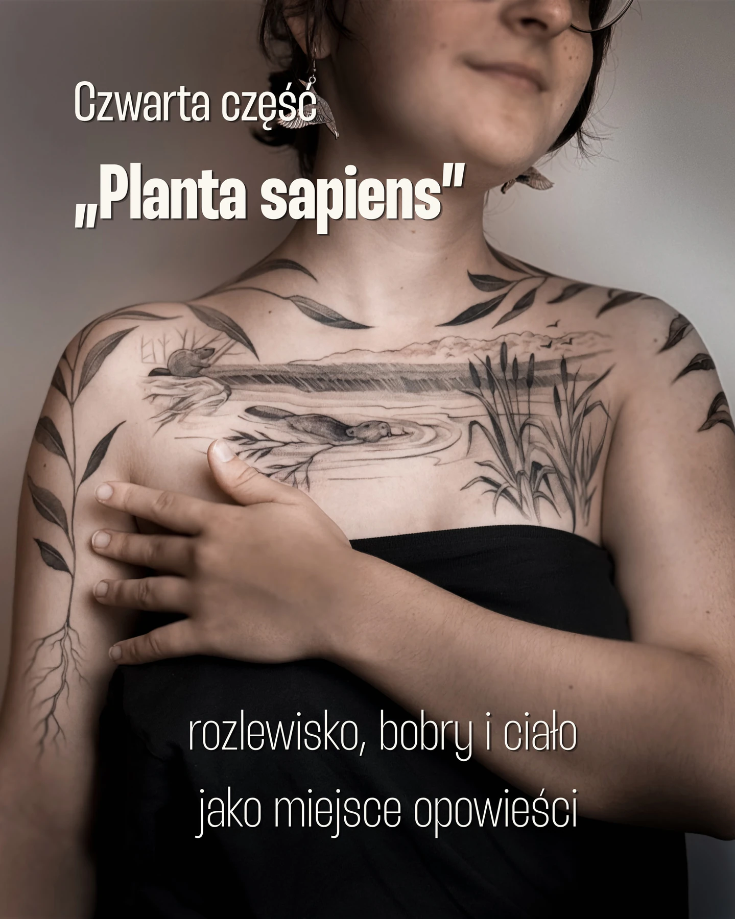 Tatuaż na dekolcie i ramionach przedstawiający rozlewisko z bobrami, trzcinami i wierzbowe gałązki tworzące ramę kompozycji.