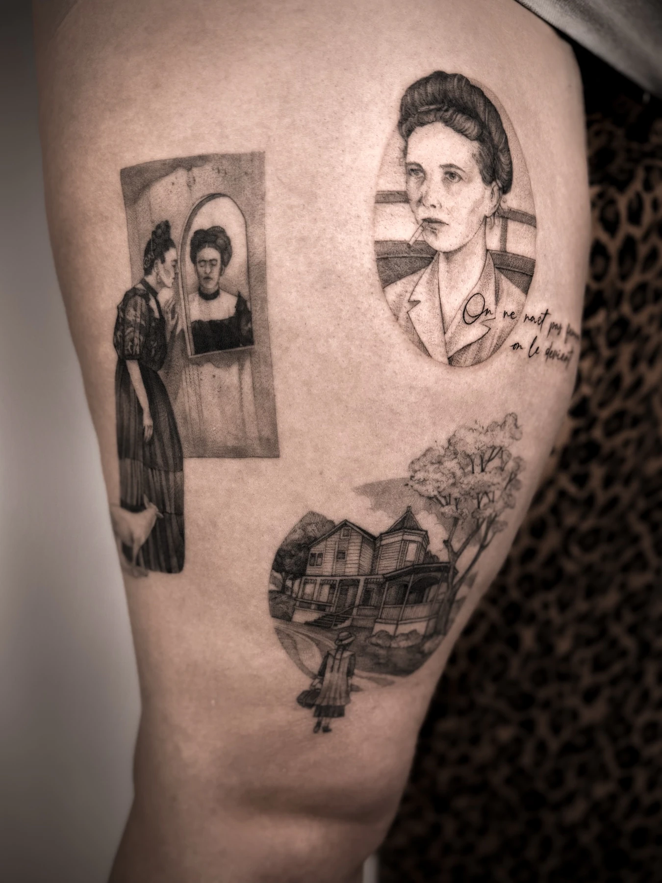 Czarno-szare tatuaże na udzie przedstawiające kobiece postacie, portret kobiety, scenę z domem i drzewem oraz sylwetkę kobiety z psem.
